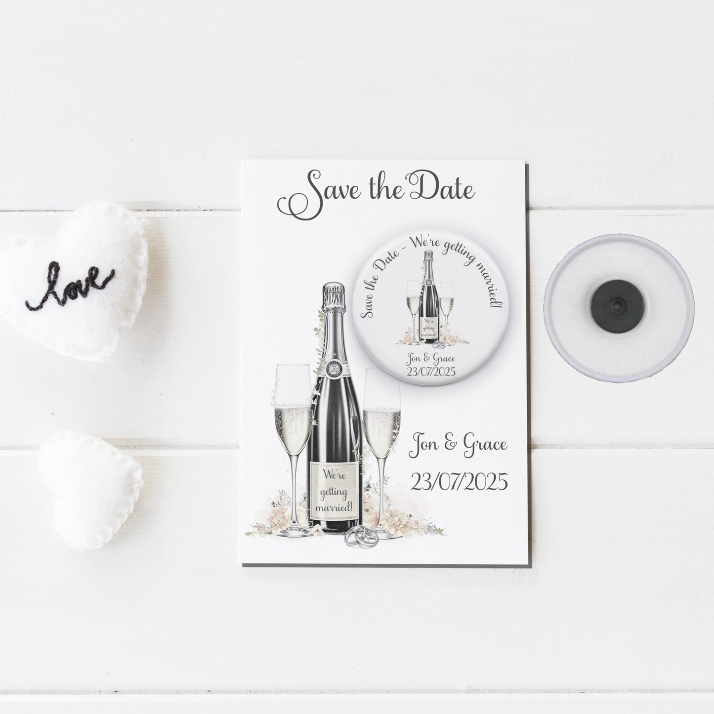 Save the date badge mirror featuring an image of champagne and glasses and personalised with names and wedding date badge on a backing card with the same design