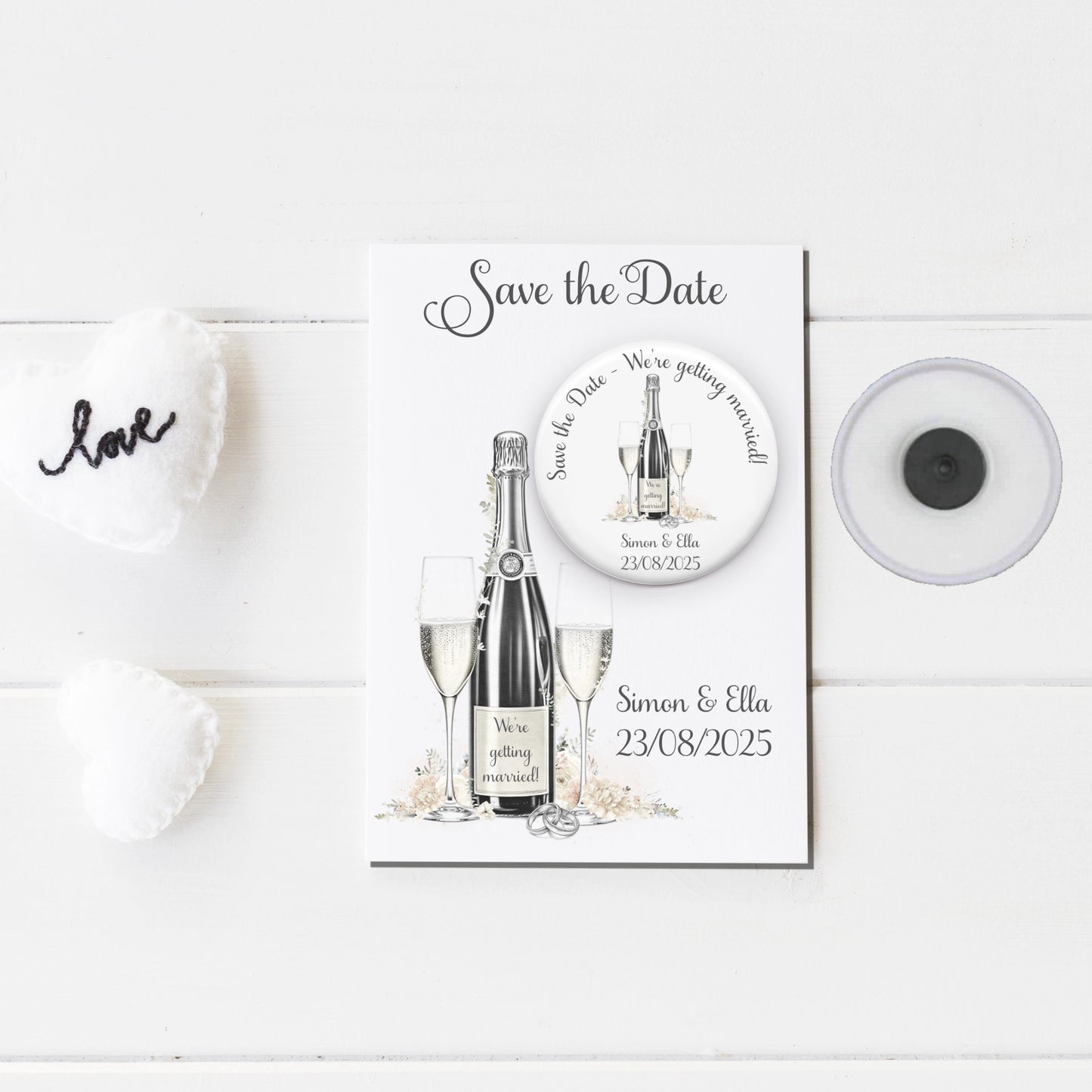 Save the date badge mirror featuring an image of champagne and glasses and personalised with names and wedding date badge on a backing card with the same design