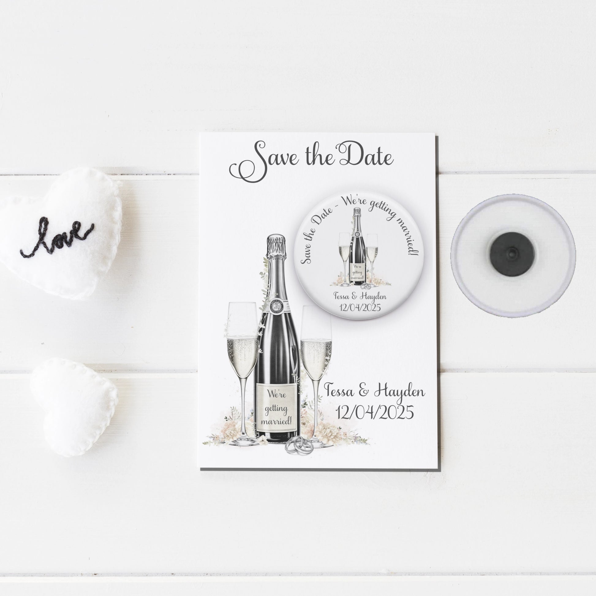 Save the date badge mirror featuring an image of champagne and glasses and personalised with names and wedding date badge on a backing card with the same design