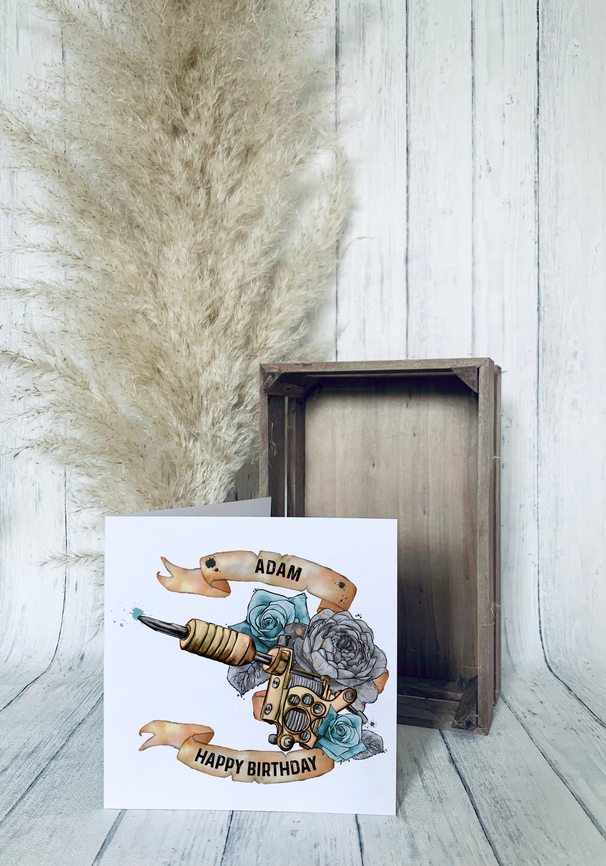 Birthday greeting card that can be personalised featuring a watercolour floral tattoo gun in blue